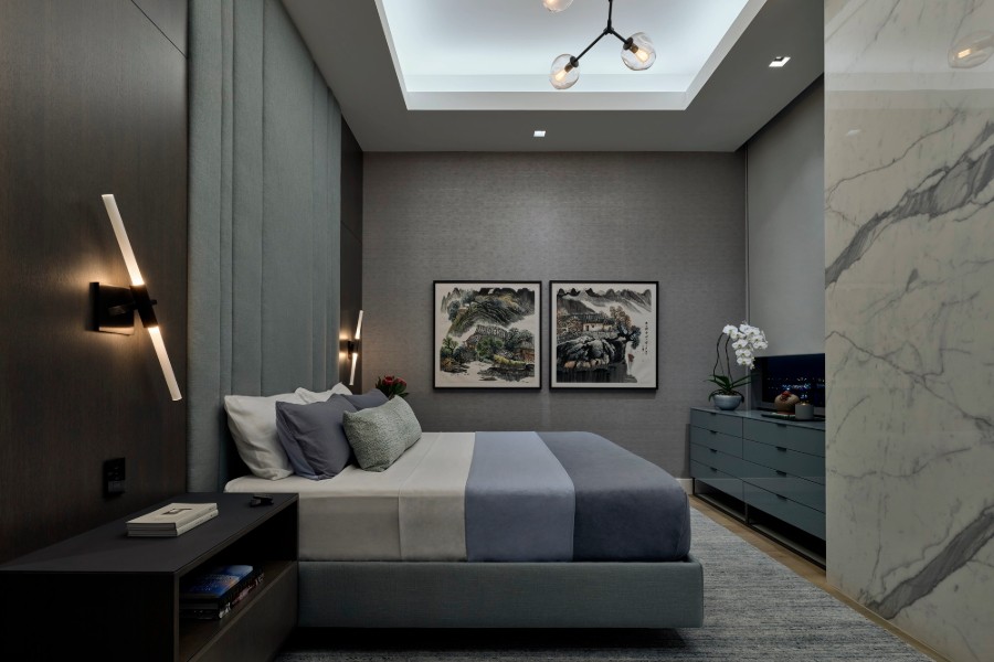 Modern bedroom showcasing a marble wall, a comfortable bed, and Lutron lighting.